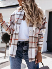 Donna con camicia a quadri beige e arancione, jeans blu, maglietta bianca. Moda autunnale casual, look trendy e moderno.