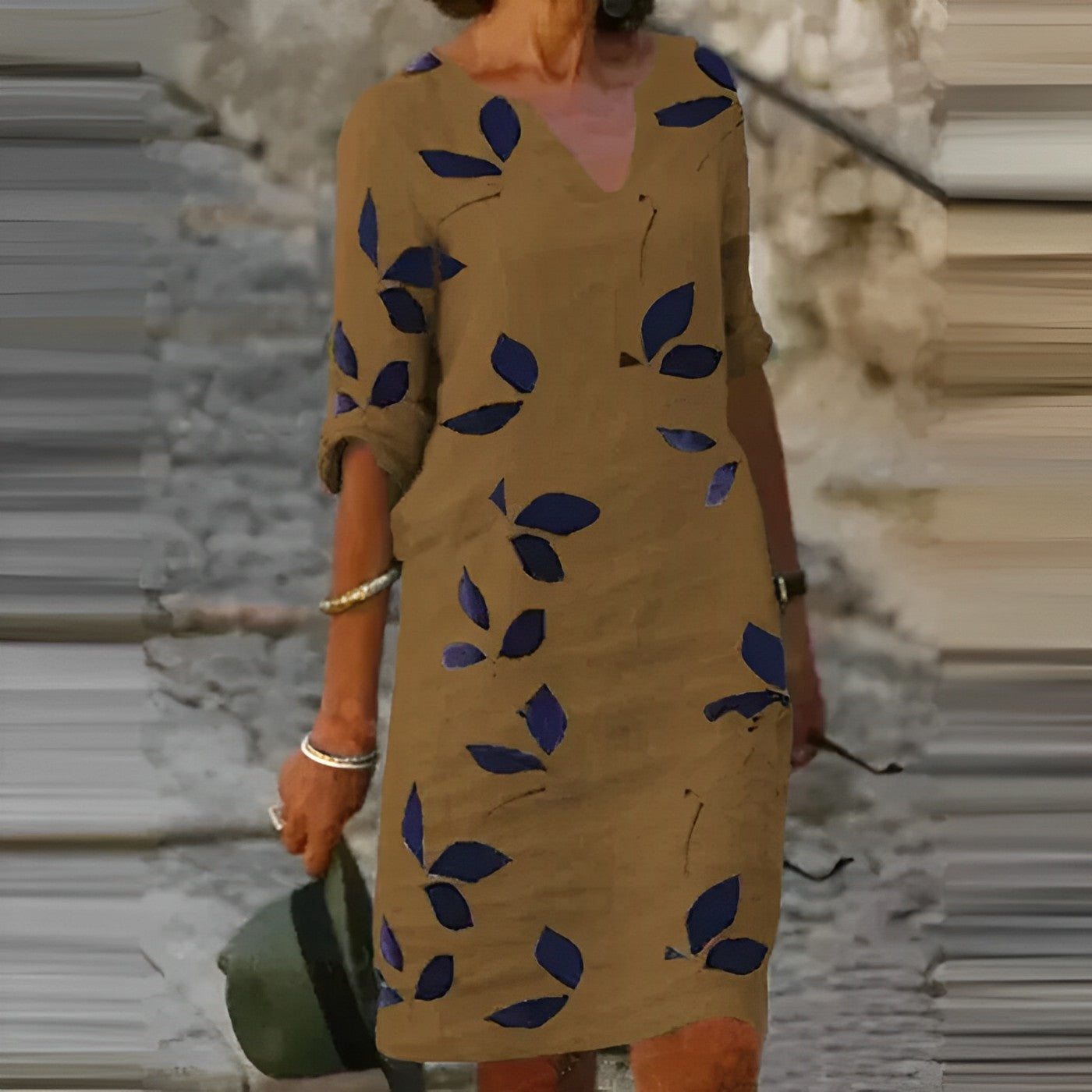 Abito casual marrone con motivo a foglie blu, maniche arrotolate, indossato da donna all'aperto. Moda estiva, abbigliamento femminile elegante.