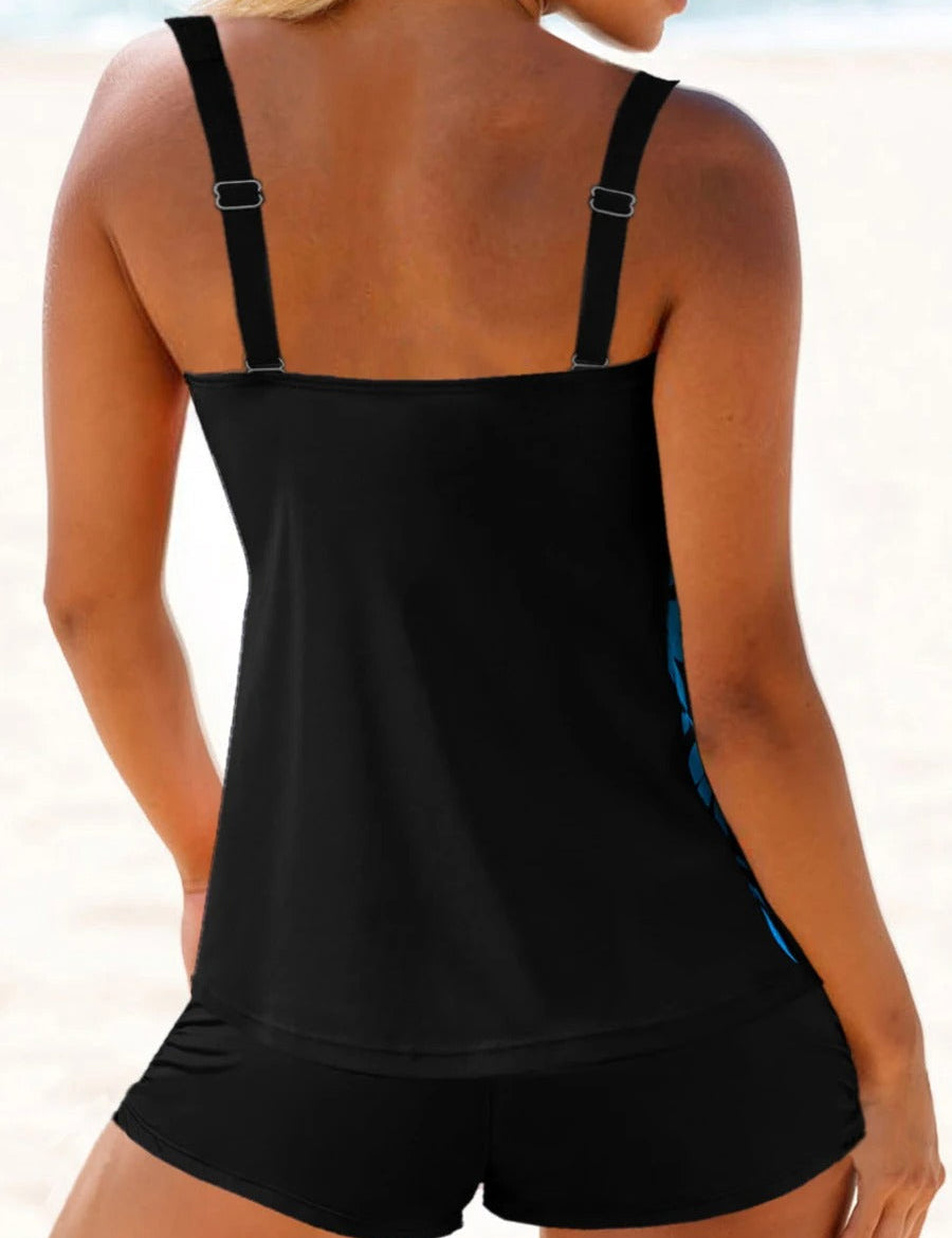 Donna in costume da bagno nero a due pezzi sulla spiaggia, top con spalline regolabili e pantaloncini. Moda mare, abbigliamento estivo donna.