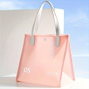 Borsa trasparente rosa con manici bianchi, design moderno, ideale per viaggi e shopping. Accessorio moda elegante e funzionale.