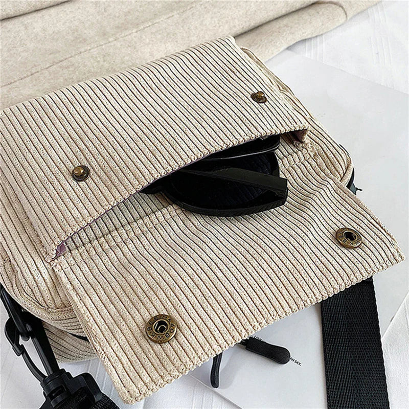 Borsa a tracolla in tessuto a coste beige con chiusura a bottoni, tracolla nera regolabile e occhiali da sole all'interno. Accessorio moda casual.