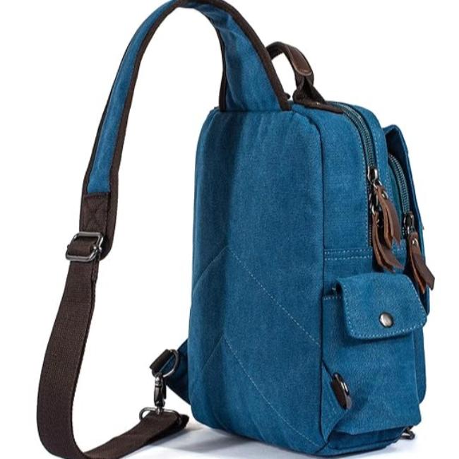 Zaino monospalla in tela blu con tasche multiple, cerniere robuste e tracolla regolabile. Ideale per viaggi, escursioni e uso quotidiano.