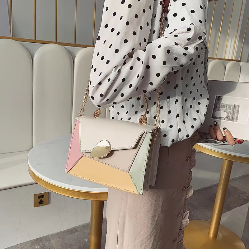 Borsa a tracolla multicolore con chiusura dorata, indossata da una persona con camicia a pois. Design elegante, perfetta per moda femminile.