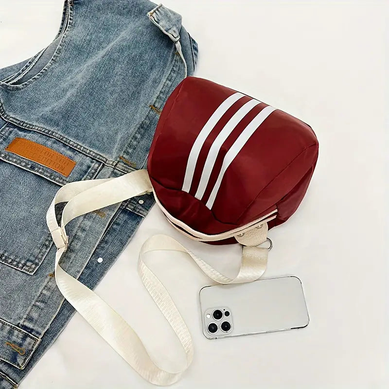 Zaino rosso con strisce bianche, accanto a giacca di jeans e smartphone bianco. Design moderno, ideale per moda casual e accessori di tendenza.