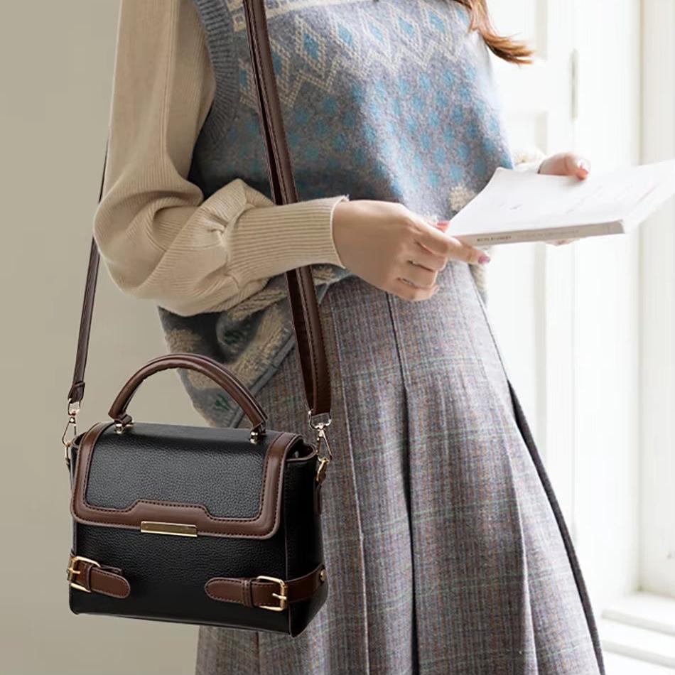 Borsa a tracolla in pelle nera e marrone, design elegante con fibbie dorate, indossata da donna in abbigliamento autunnale. Accessorio moda chic.