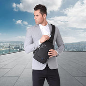 Uomo elegante con giacca grigia indossa borsa a tracolla nera su terrazza panoramica. Accessorio moda maschile, stile urbano, vista città.