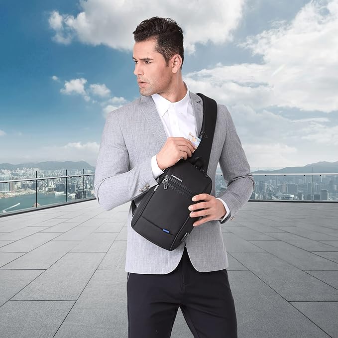 Uomo elegante con giacca grigia indossa borsa a tracolla nera su terrazza panoramica. Accessorio moda maschile, stile urbano, vista città.