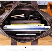 Borsa in pelle marrone aperta, mostra capacità interna con laptop, libri e accessori. Ideale per computer 14 pollici e viaggi quotidiani.