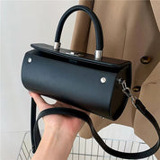 Borsa a tracolla cilindrica nera in pelle, design elegante con manico superiore e chiusura metallica, perfetta per moda donna e accessori di tendenza.