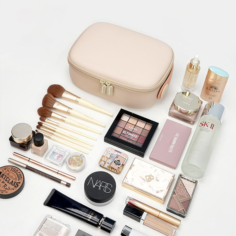 Set di cosmetici e accessori trucco su sfondo bianco, include pennelli, palette ombretti, fondotinta, rossetti e crema SK-II, con borsa beige.