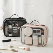 Due beauty case trasparenti con cosmetici, uno nero e uno beige, su un tavolo bianco. Ideali per organizzare trucchi e accessori da viaggio.