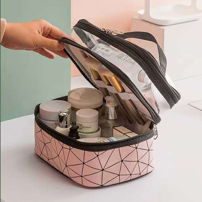 Borsa cosmetica rosa con motivo geometrico, doppio scomparto trasparente, contenente pennelli trucco, creme e flaconi. Ideale per organizzare cosmetici.