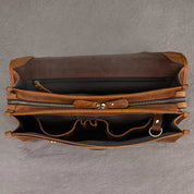 Borsa in pelle marrone aperta, vista dall'alto, con scomparti interni e cerniera. Elegante e spaziosa, ideale per lavoro o viaggio.