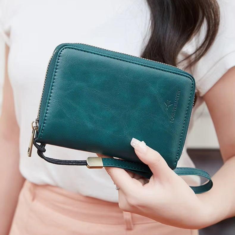 Portafoglio donna in pelle verde con cerniera, design compatto, cinturino da polso, ideale per carte e contanti, accessorio moda elegante.