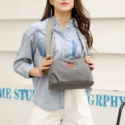 Donna con borsa a tracolla grigia in tessuto, indossa camicia di jeans. Accessorio moda casual, ideale per shopping e uscite quotidiane.