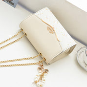 Borsa a tracolla elegante in pelle bianca con catena dorata e ciondolo perle, design moderno, accessorio moda donna, perfetta per ogni occasione.
