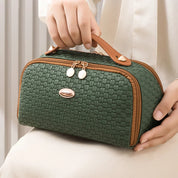 Borsa a mano verde intrecciata, dettagli in pelle marrone, chiusura a zip dorata, design elegante, accessorio moda donna, stile casual chic.