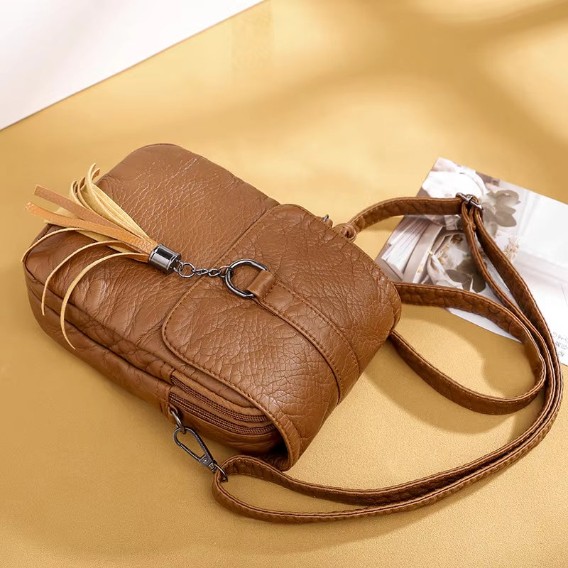 Borsa a tracolla in pelle marrone con nappina decorativa, design elegante e moderno, ideale per moda donna. Accessorio versatile e di tendenza.