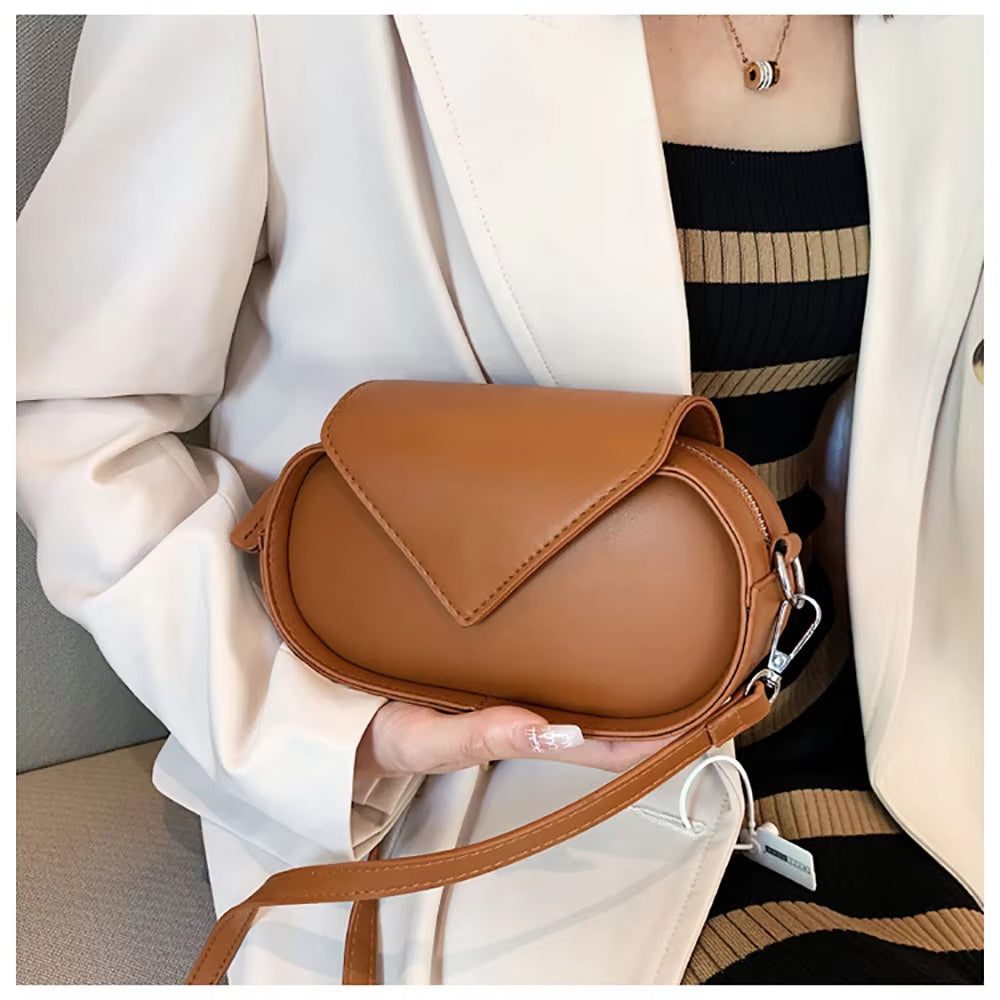 Borsa a tracolla in pelle marrone, design elegante e moderno, indossata da una donna in abito a righe. Accessorio moda femminile di tendenza.