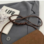 Giacca grigia elegante con libro "LIFE", borsa marrone e accessorio trasparente. Moda autunnale, abbigliamento casual chic, stile contemporaneo.