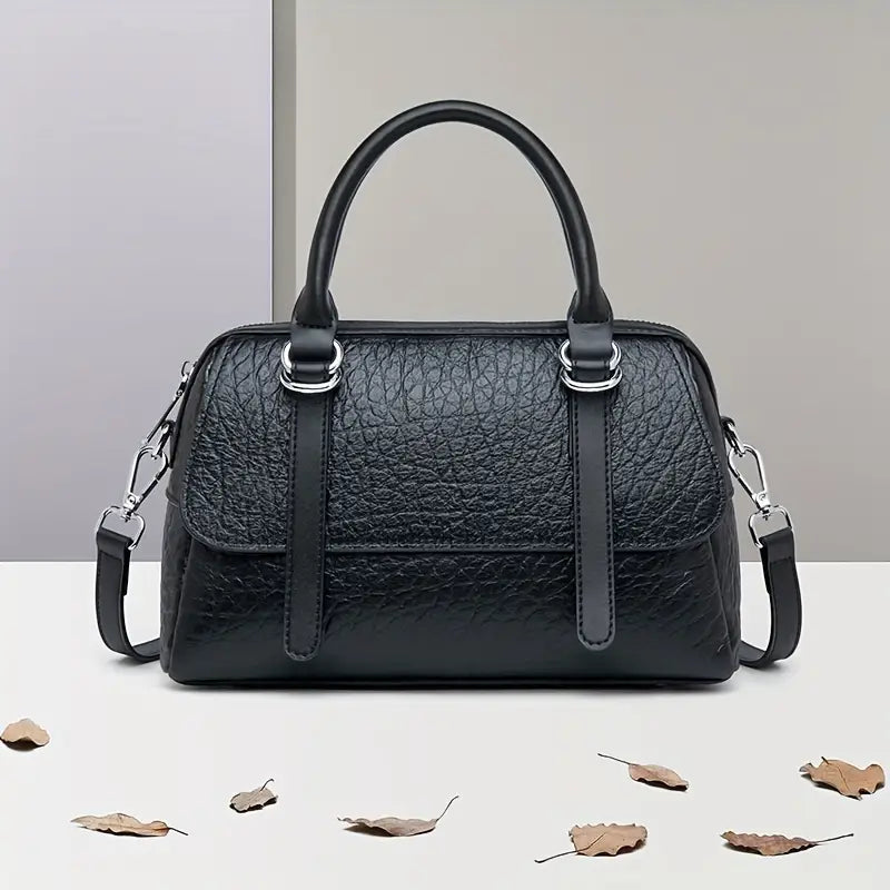 Borsa a mano in pelle nera su sfondo neutro, design elegante con manici e tracolla regolabile. Accessorio moda donna, stile classico.