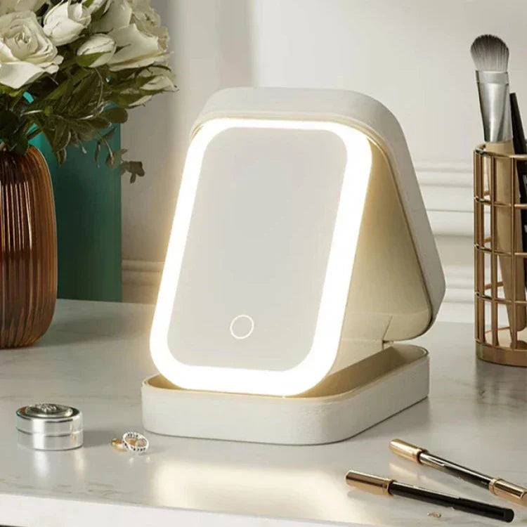 Specchio cosmetico LED rettangolare su tavolo da trucco, circondato da fiori bianchi e accessori di bellezza. Design moderno, illuminazione regolabile.