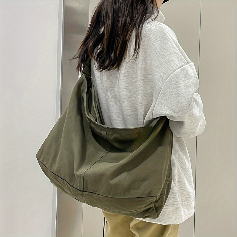 Donna con borsa a tracolla verde oliva, indossa felpa grigia e pantaloni beige. Moda casual, accessorio pratico e versatile per tutti i giorni.