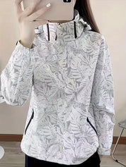 Giacca a vento donna bianca con stampa foglie tropicali, cappuccio regolabile, tasche con zip, ideale per attività outdoor e moda casual.