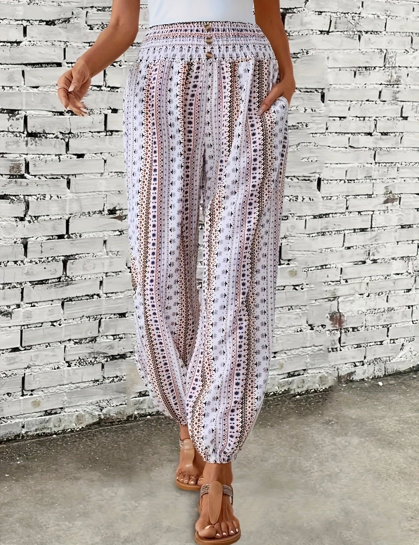 Pantaloni estivi donna a palazzo, bianchi con motivo geometrico nero, elastico in vita, tasche laterali, indossati con sandali marroni.