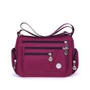 Borsa a tracolla viola con tasche multiple e cerniere, design elegante e funzionale, ideale per donna. Accessorio moda versatile e pratico.