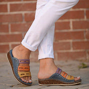 Sandali estivi multicolore da donna, con zeppa in sughero e cinturini in pelle, indossati con pantaloni bianchi. Calzature moda comode e casual.