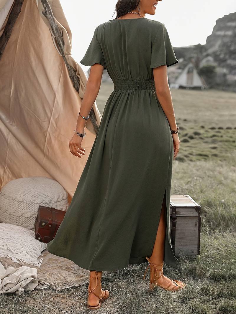 Abito lungo verde oliva con spacchi laterali, indossato da una donna all'aperto vicino a una tenda. Stile boho chic, perfetto per l'estate.