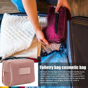 Persona che mette una borsa da toilette rossa in una valigia aperta con vestiti. Borsa cosmetica da viaggio, pratica e resistente, ideale per organizzare articoli da bagno.