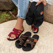 Donna con sandali estivi intrecciati in tre colori: nero, rosso e marrone. Scarpe comode su tappeto di paglia, moda casual per l'estate.