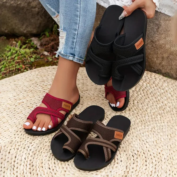 Donna con sandali estivi intrecciati in tre colori: nero, rosso e marrone. Scarpe comode su tappeto di paglia, moda casual per l'estate.