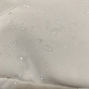 Tessuto impermeabile beige con gocce d'acqua, resistente all'acqua, ideale per abbigliamento outdoor e arredamento esterno.