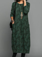 Abito lungo verde con motivo floreale, maniche lunghe, tasche frontali, collana pendente. Elegante e casual, perfetto per l'autunno.
