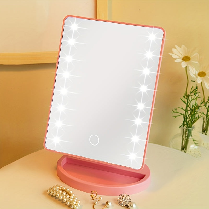 Specchio cosmetico LED rettangolare rosa, con luci regolabili, su tavolo da trucco. Accessori per il trucco e fiori sullo sfondo.