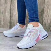 Scarpe da ginnastica bianche e rosa da donna, suola spessa, indossate con jeans. Design moderno, comode per sport e tempo libero.
