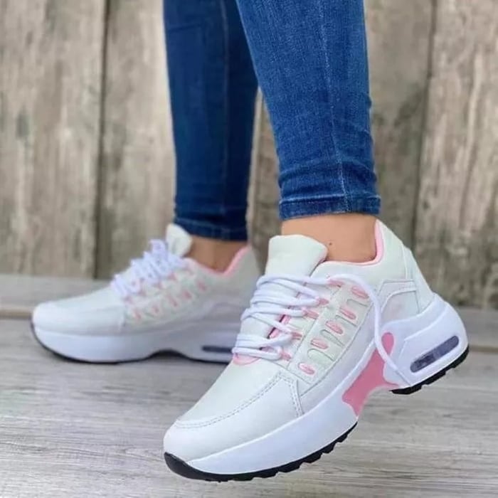 Scarpe da ginnastica bianche e rosa da donna, suola spessa, indossate con jeans. Design moderno, comode per sport e tempo libero.