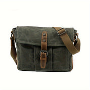 Borsa a tracolla in tela verde militare con chiusura a fibbia, tasca frontale e tracolla regolabile marrone. Stile casual e resistente.