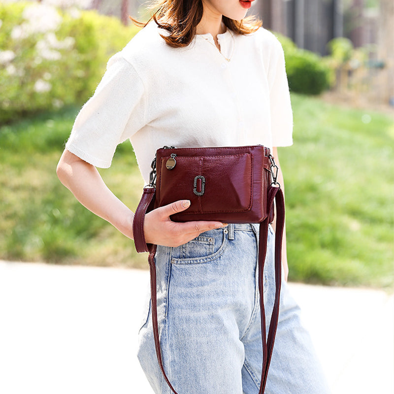 Donna con borsa a tracolla in pelle marrone, indossa jeans e maglietta bianca. Accessorio moda elegante per look casual.