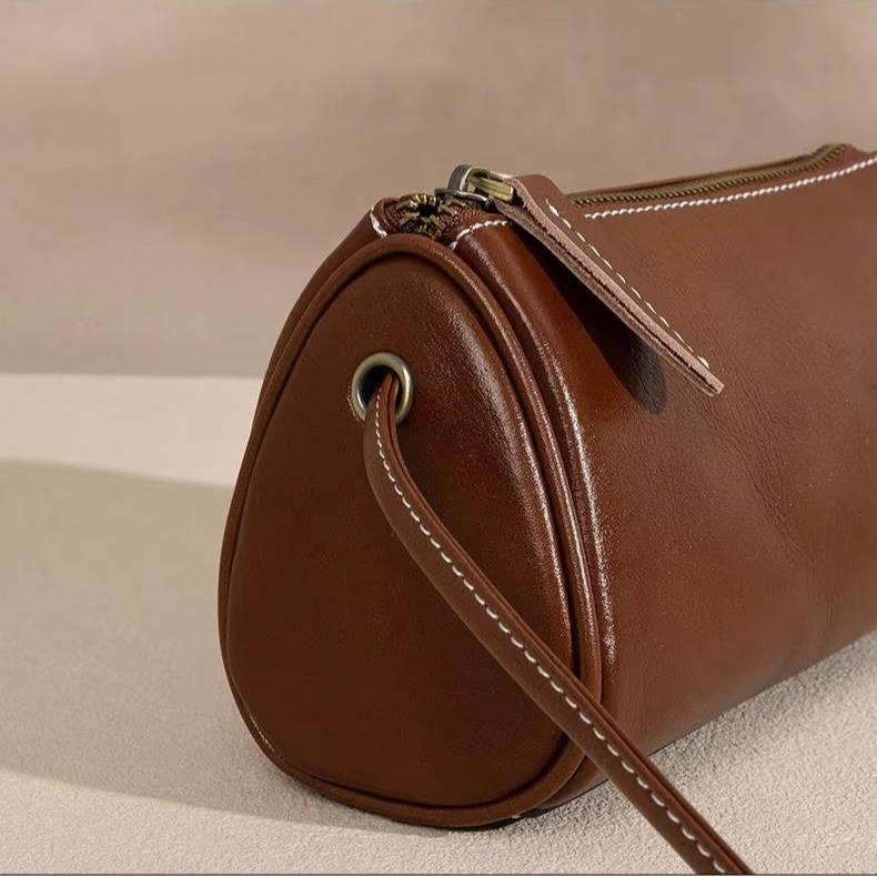 Borsa a tracolla cilindrica in pelle marrone, chiusura con zip, design elegante e moderno, accessorio moda donna, perfetta per ogni occasione.