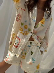 Camicia e pantaloncini in seta con stampa colorata di cuori, sole e foglie. Moda estiva donna, abbigliamento casual elegante.