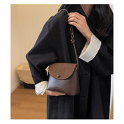 Borsa a tracolla marrone in pelle, design elegante, indossata da una donna in abito nero. Accessorio moda femminile, stile casual chic.