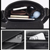 Borsa a tracolla in pelle nera con scomparti interni, contenente smartphone, notebook, portafoglio e accessori. Design elegante e funzionale.