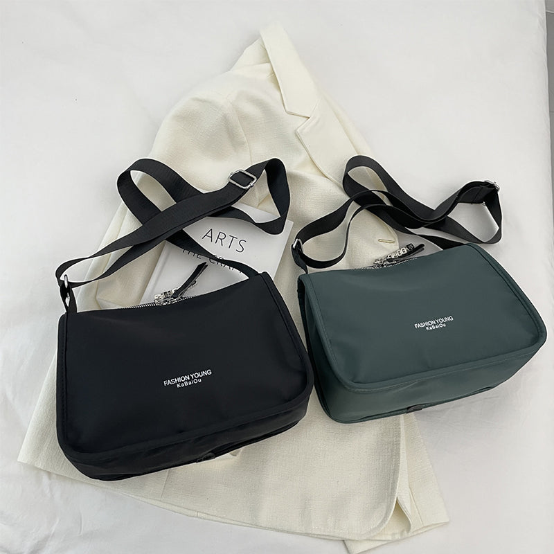 Due borse a tracolla nere e verdi su giacca bianca, design moderno, tessuto resistente, moda casual, accessori eleganti per donna.