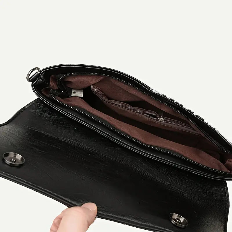 Borsa a tracolla in pelle nera aperta, interno foderato marrone con tasche multiple e chiusura a bottone magnetico. Accessorio moda elegante e pratico.