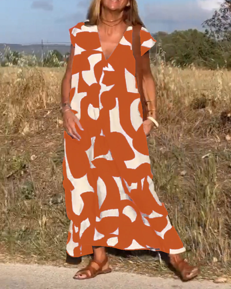 Donna con abito lungo estivo arancione e bianco a motivi astratti, sandali marroni, in un campo all'aperto. Moda femminile, abbigliamento estivo.