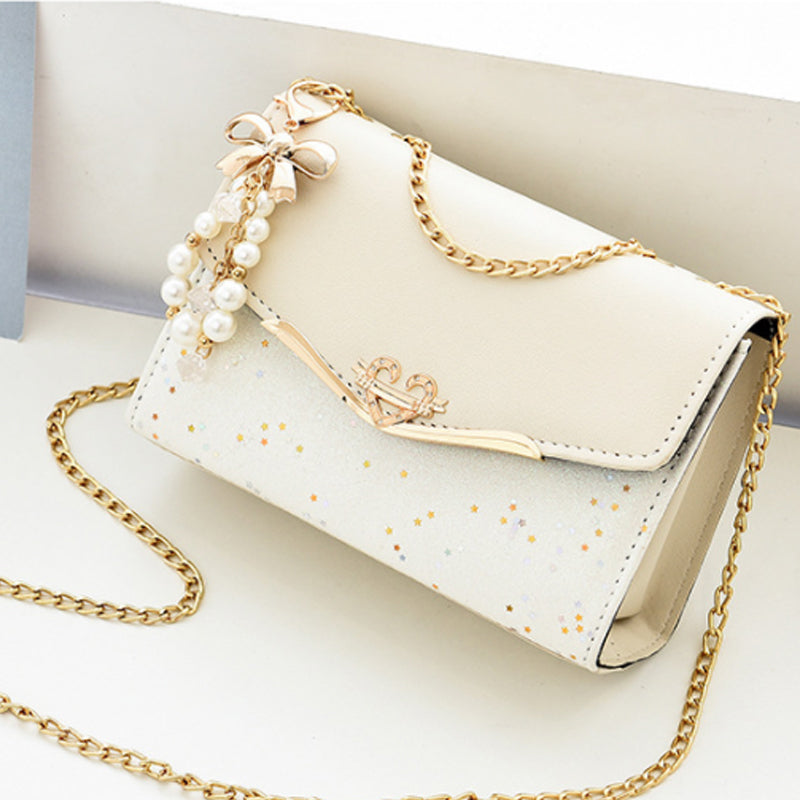 Borsa a tracolla elegante bianca con catena dorata, decorata con perle e fiocchi. Accessorio moda donna, perfetto per eventi speciali.